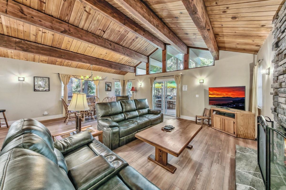 A spacious living room with a wooden ceiling, leather sofa, a coffee table, and a TV.