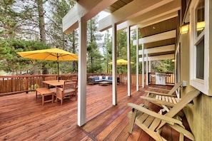 Una terraza de madera con mobiliario exterior, incluyendo una mesa y sillas, y dos sombrillas amarillas.