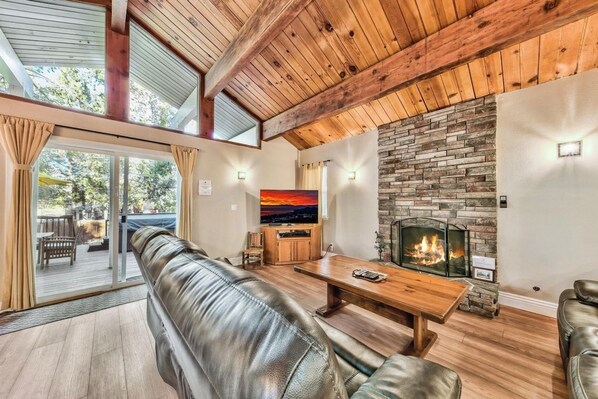 Una sala de estar moderna con un sofá de cuero, una mesa de centro de madera, una chimenea de piedra y un televisor.