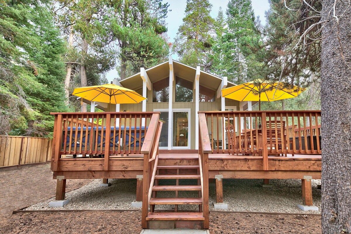 A wooden deck with a staircase leading to a covered area, surrounded by trees.