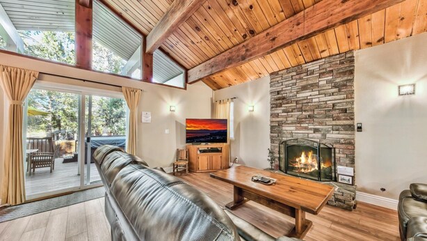 Una sala de estar acogedora con un sofá de cuero, una mesa de centro de madera, una chimenea de piedra y un televisor.