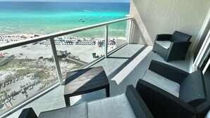 A balcony with wicker furniture overlooking a beach with clear turquoise water and a sandy shore. - Amazing 14th floor views! Perfect for Couples! 4344BS2 (Miramar Beach)