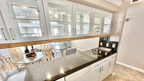 A modern kitchen with white cabinetry, a granite countertop, and a dining area visible through the glass doors. - Amazing 14th floor views! Perfect for Couples! 4344BS2 (Miramar Beach)