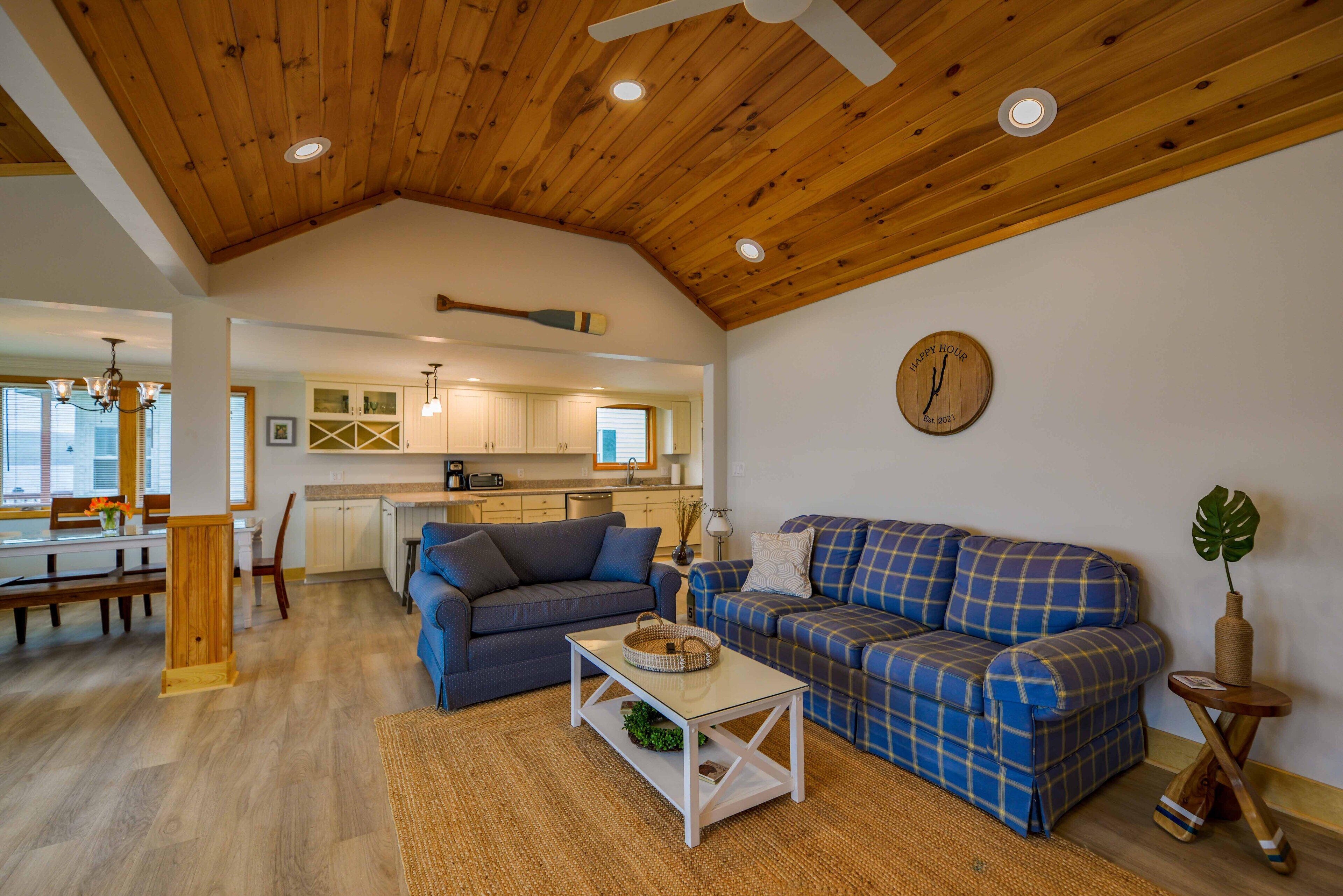 Ein großzügiger Wohnbereich mit hoher Decke, einem Esstisch, Sofas und einer Küche im Hintergrund.