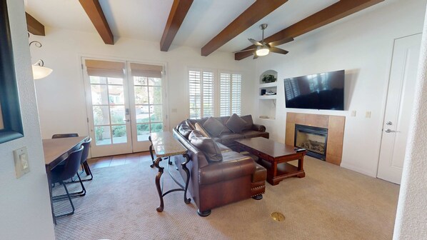 A living room with a sectional sofa, a coffee table, a TV, and a fireplace.
