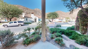 A residential street with houses, parked cars, and a speed limit sign.