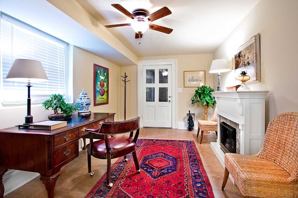 Une pièce avec un bureau, un fauteuil en cuir et une cheminée.