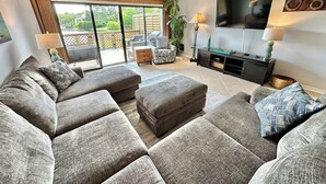 A living room with a sectional sofa, a flat-screen TV, and a ceiling fan. - Fresh updates with Golf Cart! 5197 BW (Miramar Beach)