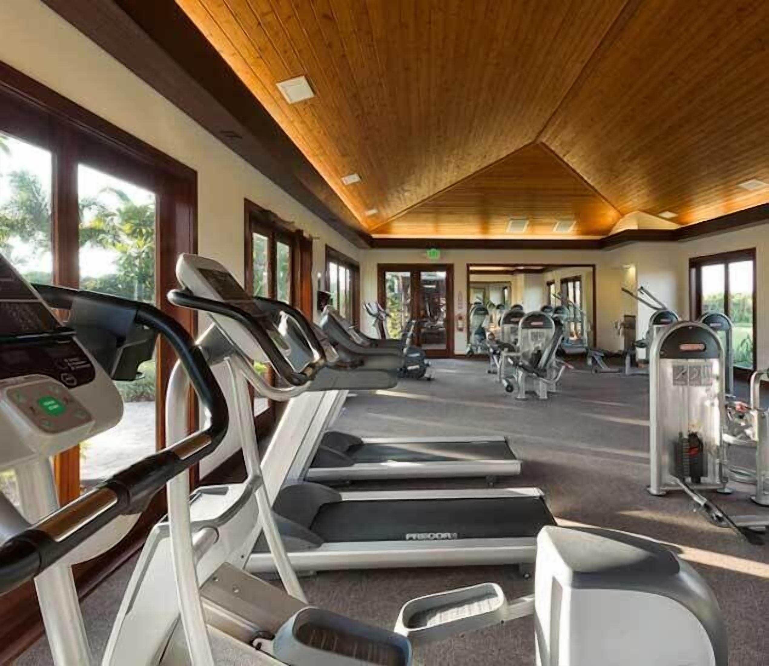 Un gimnasio con cintas de correr, elípticas y equipos de pesas.