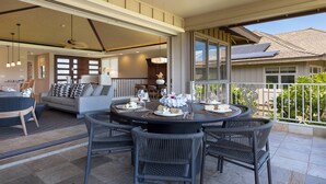 A spacious patio with a round table set for dining, surrounded by wicker chairs. - Local Luxury Living! (Kamuela)