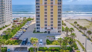 Ein Hochhaus-Hotel mit Innenhof, Parkplatz und Blick auf den Strand.