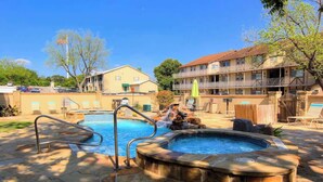 A swimming pool with a hot tub, stone steps, and a wooden deck. - WW C302 Gracelanda (New Braunfels)