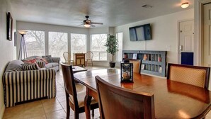 A spacious living room with a dining table, striped sofa, and a ceiling fan. - WW C302 Gracelanda (New Braunfels)