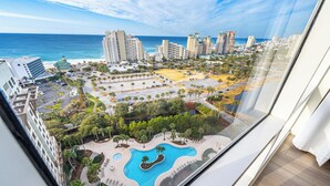A high-rise hotel with a pool, palm trees, and a view of the beach and ocean.