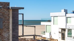 Ein modernes Gebäude mit Steinverkleidung und einem Balkon mit Blick auf einen Strand.