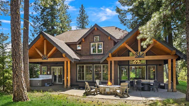 A log cabin with a stone fireplace, outdoor seating, and large windows. - Must See Suncadia Retreat! 3 Masters * Hot Tub * Game Room * On the Course! (Cle Elum)