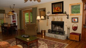 A cozy living room with a fireplace, wooden furniture, and a dining area.