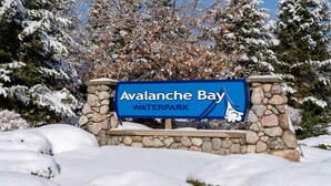 Un panneau indiquant le parc aquatique Avalanche Bay, entouré d’arbres couverts de neige.