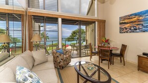 Uma sala ampla com uma grande janela com vista panorâmica, um sofá confortável, uma mesa de jantar com cadeiras e uma pequena mesa lateral.