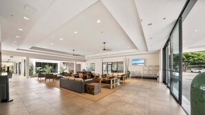 Eine großzügige Lobby mit hoher Decke, großen Fenstern und einer Sitzecke mit Sofas und Tischen.