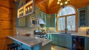 A kitchen with wooden walls, a central island, and a large window. - Chipmunk Chase in Gated Smoky Mountain Retreat Community (MAGGIE VALLEY)