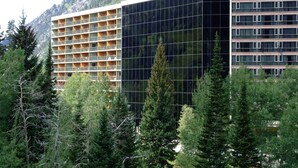 A modern hotel with a glass facade, multiple floors, and a mountainous backdrop. - Prime Ski Week at Snowbird's Cliff Club Sleeps 6 in 1bedroom (Sandy)
