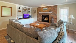 A living room with a fireplace, a television, and a sofa. - Lakefront Rumbling Bald Retreat, HotTub, Kayaks, SUP's, Floating Dock (Lake Lure)