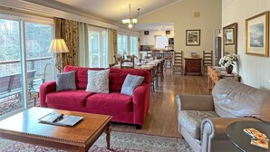 A spacious living room with a red sofa, a grey sofa, and a beige sofa. There is a wooden coffee table in the center. - Lakefront Rumbling Bald Retreat, HotTub, Kayaks, SUP's, Floating Dock (Lake Lure)