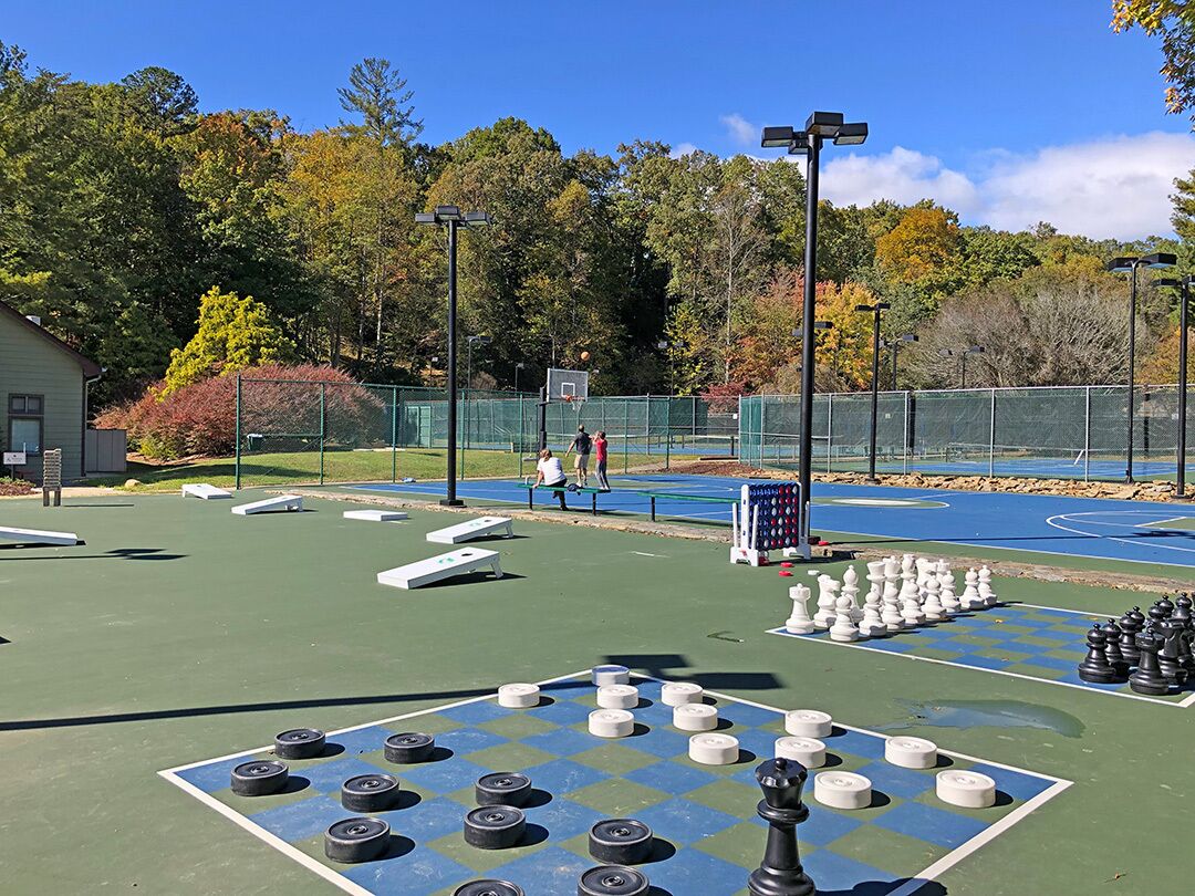 Un jeu d’échecs installé sur un terrain de sport, avec un panier de basketball en arrière-plan.