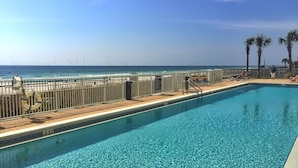 A swimming pool with a view of the ocean, a lifebuoy, and a sign indicating pool rules. - Platinum, King Masters, Walk-In Showers, End-Unit Balcony, Free Beach Chairs! (Panama City Beach)
