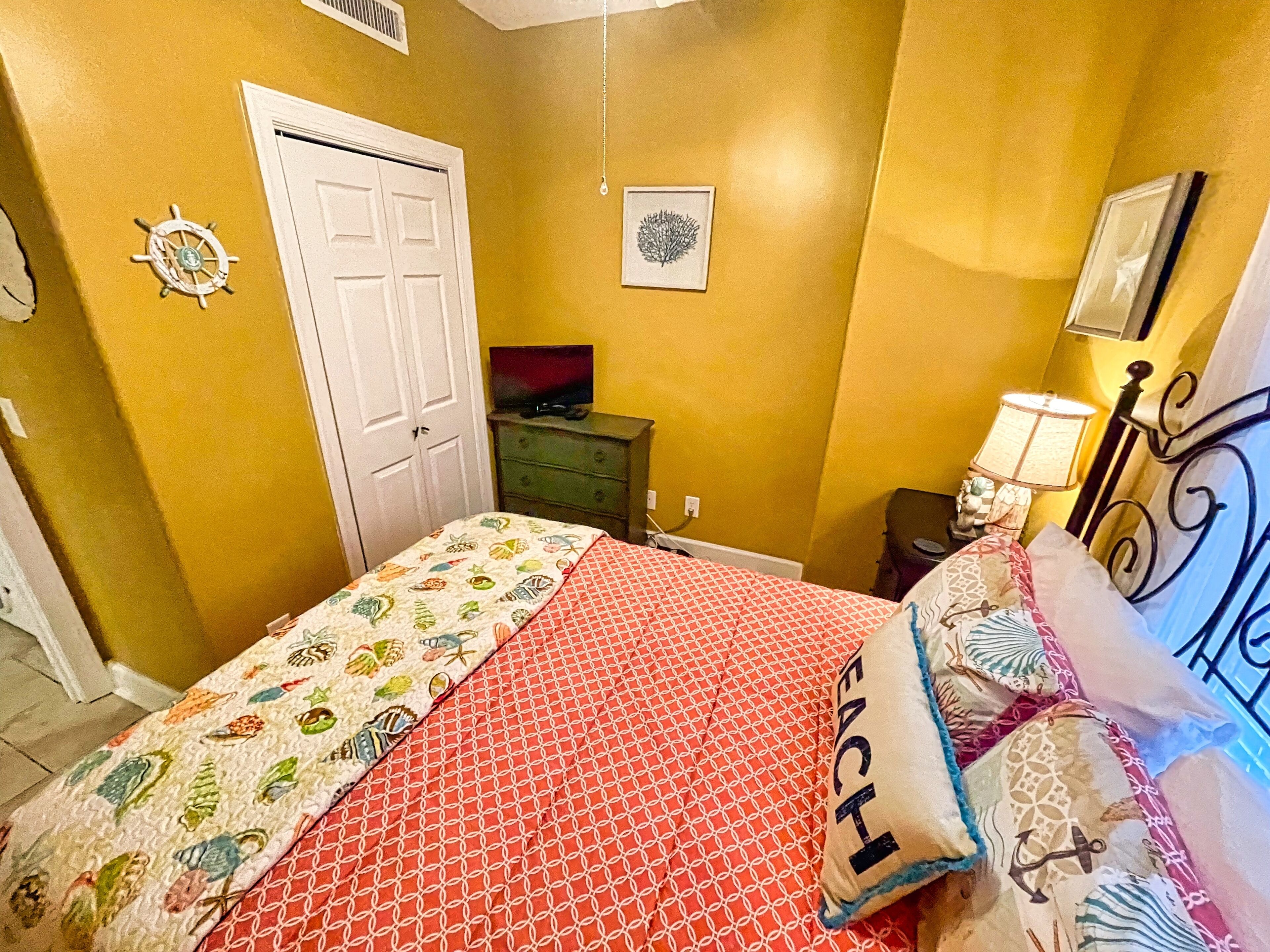 A bedroom with a bed, a dresser, a television, and a door.
