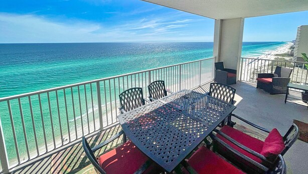 A balcony with a view of the ocean and beach, furnished with a table and chairs. - Platinum, King Masters, Walk-In Showers, End-Unit Balcony, Free Beach Chairs! (Panama City Beach)