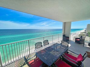 Un balcon avec vue sur l’océan et la plage, aménagé avec une table et des chaises.