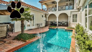 Piscina con fontana, circondata da un patio con sedie e tavolo, e un'area balcone coperta.
