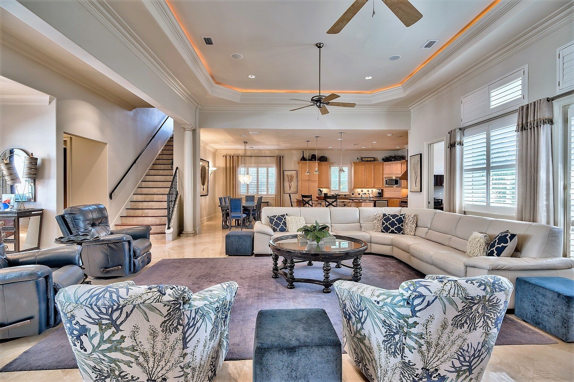 A spacious living room with a large sofa, a coffee table, and a dining area in the background.