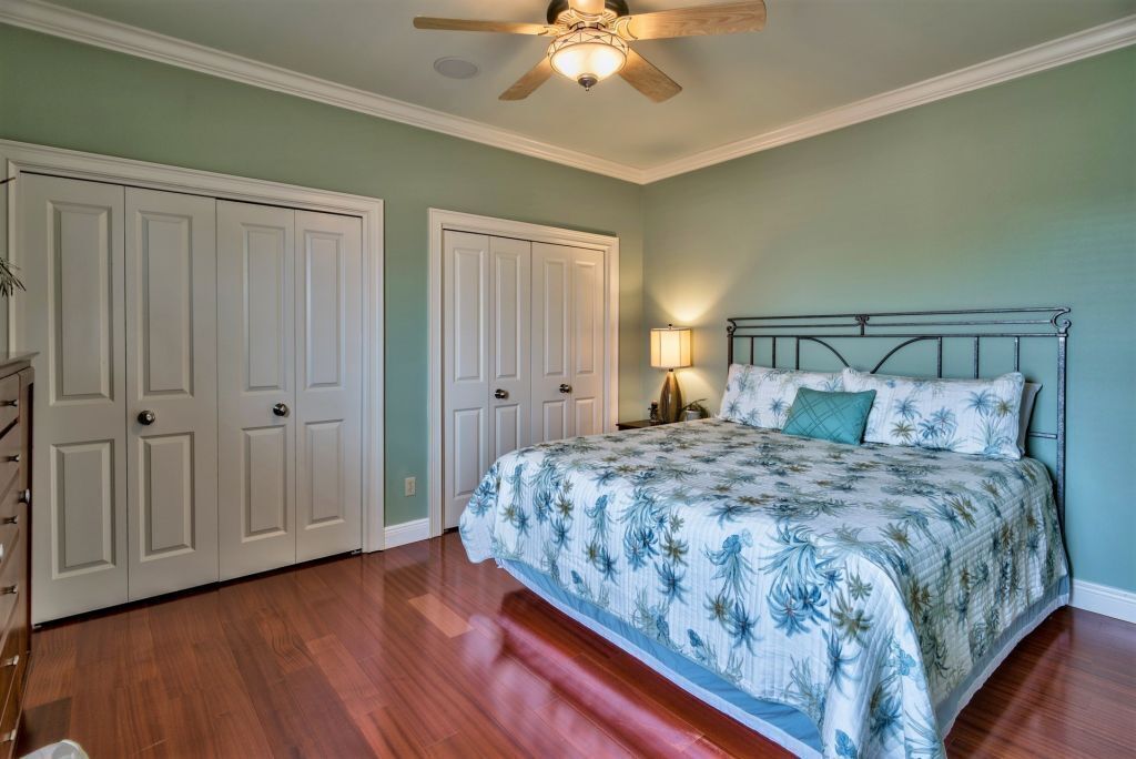 A bedroom with a bed, a ceiling fan, and a nightstand with a lamp.