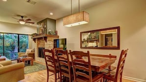 Un comedor con mesa y sillas de madera, chimenea y un espejo grande en la pared.