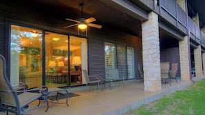 Un patio cubierto con mobiliario exterior, ventilador de techo y vista hacia el interior.