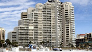A high-rise hotel with multiple balconies, a beach view, and a small beachside structure. - Dazzling Beach View 6 Seat Golf Cart included! 4321 BS2 (Miramar Beach)