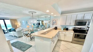 A modern kitchen with white cabinets, stainless steel appliances, and a large island. - Dazzling Beach View 6 Seat Golf Cart included! 4321 BS2 (Miramar Beach)