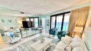 A spacious living room with a large TV, comfortable seating, and a view of the ocean. - Dazzling Beach View 6 Seat Golf Cart included! 4321 BS2 (Miramar Beach)