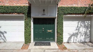 A building with a green door and two garage doors, number 425, with a small step leading up to the entrance.