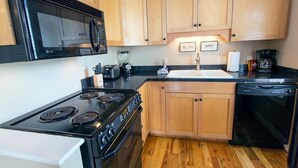 A kitchen with a stove, microwave, sink, and dishwasher.