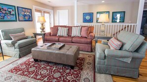 A living room with a red sofa, two armchairs, a coffee table, and a patterned rug.
