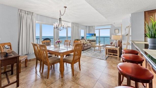 A spacious living area with a dining table, chairs, a sofa, a TV, and a balcony with a view. - Family fun with amazing amenities + Free Attraction Tickets! (Myrtle Beach)