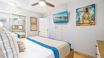 Ein Schlafzimmer mit einem Bett, einem Deckenventilator, einem Gemälde und einer Tür.