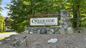 Schild für Creekside bei Boyne Mountain mit einem Steinpfeiler und Holzzaun.