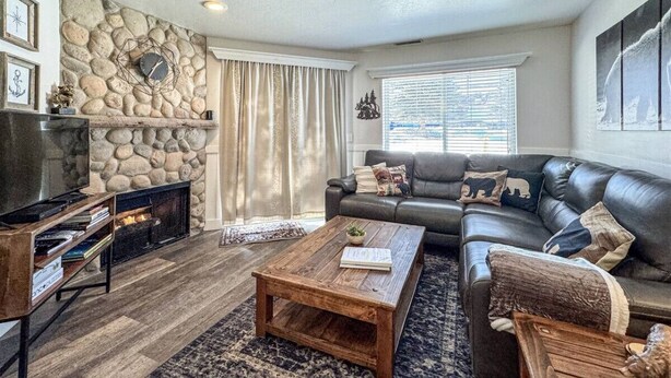 A living room with a stone fireplace, a leather sofa, a coffee table, and a television.