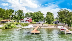 A lakeside property with docked boats, a red house, and a stone bridge. - Seneca Sunsets - Awesome Lakeside Getaway Near Geneva! (Geneva)