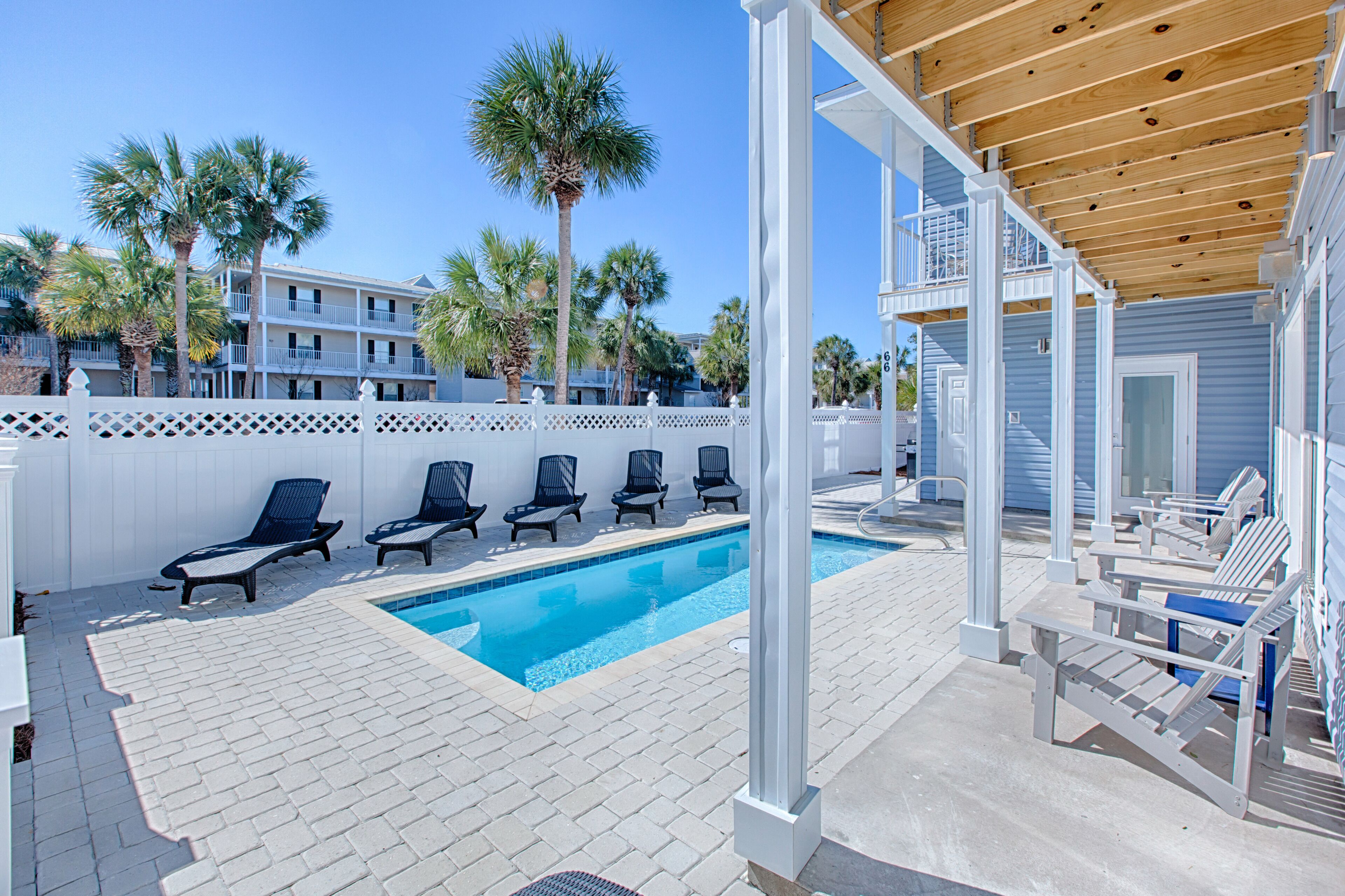 A pool area with lounge chairs and a wooden pergola.